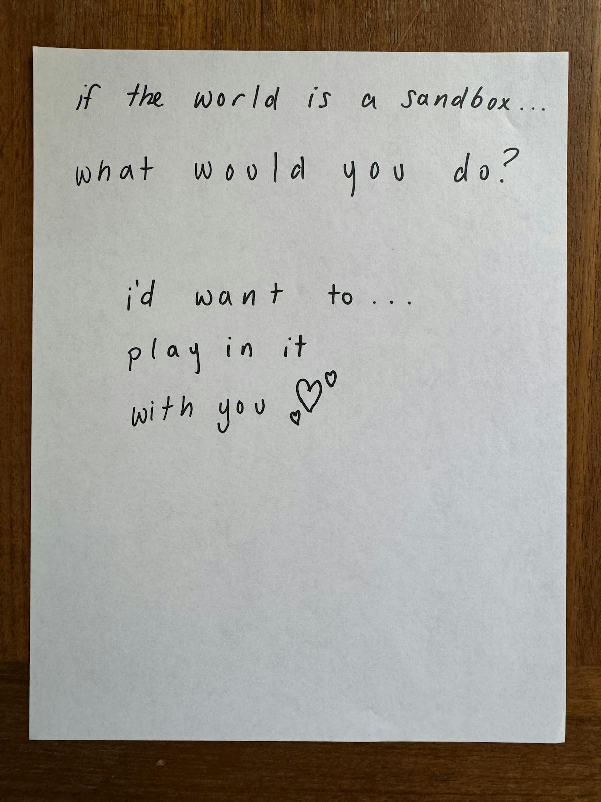 a piece of paper with the words 'if the world is a sandbox... what would you do? i'd want to... play in it with you ♥' written on it